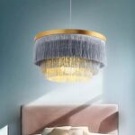 Bohemian fringed round pendant above a bed in a blue room