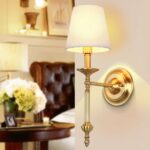 Retro-style fabric wall light, gold-colored bracket, with light on, next to a living room