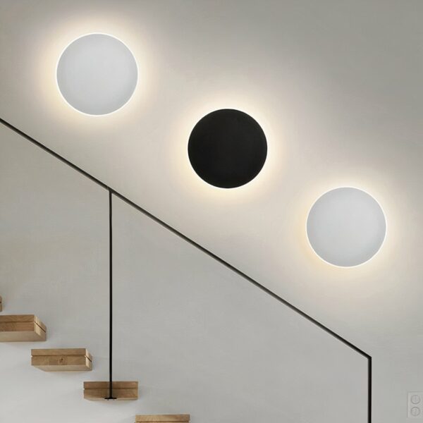 Against a white background are three round wall lights, two white and one black.