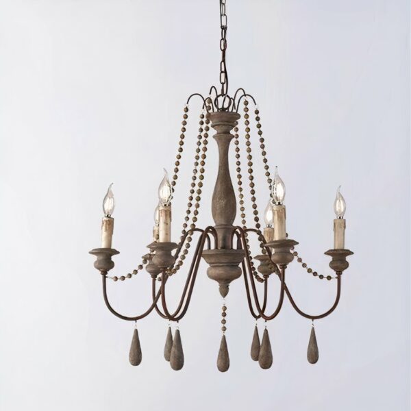 Brass and wood chandelier with 6 candles, the bulbs replace the lazy candles. Decorated with pearls, elongated ones under each candle and smaller ones on the rest of the chandelier. On a gray background.