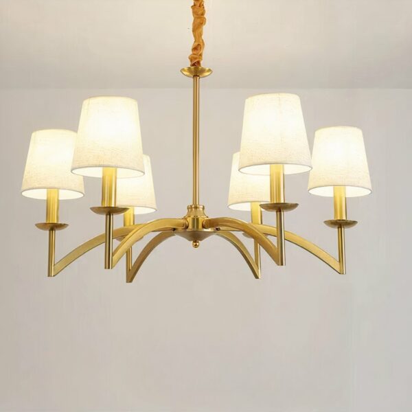 Gilded metal chandelier with 6 white fabric shades on a gray background.