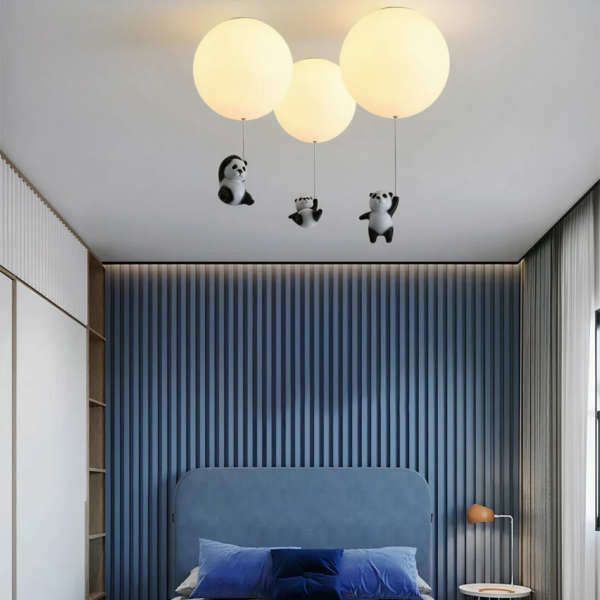 Hanging chandelier with three acrylic pandas on a blue background with a bed