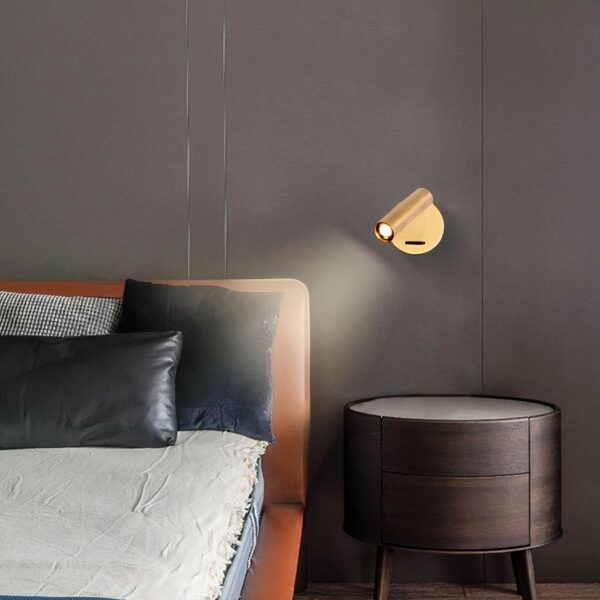 Adjustable brass wall light in gold, beside a bed above a bedside table