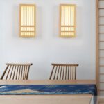 Two Japanese style wood wall lights glowing warm above a wood table