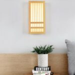 Japanese style wood wall light glowing warm beside a nightstand with a plant