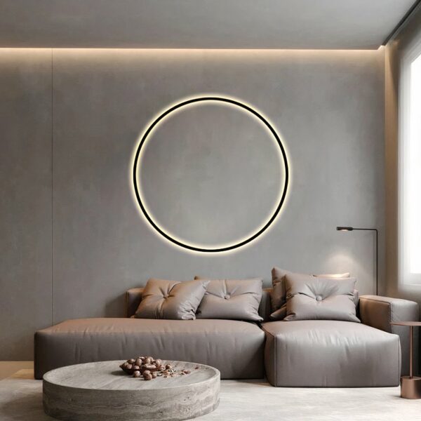 In a living room, on the wall above the grey sofa, you can see a wall light in the shape of a black circle.