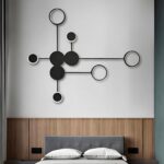 Black dot wall light glowing warm above a wood panelled bed headboard