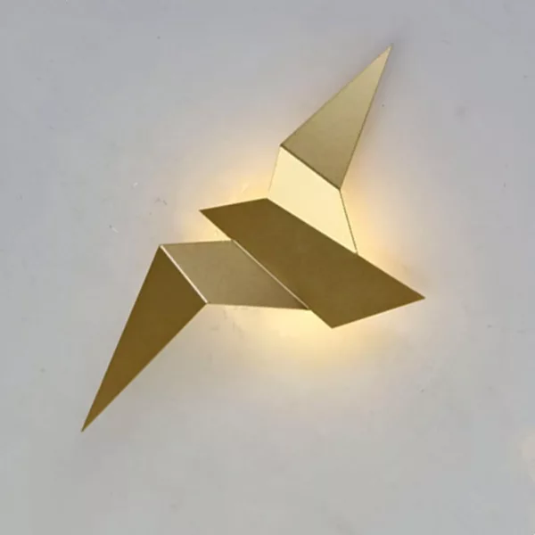 A golden origami-style wall sconce in the shape of a bird is set against a white background.