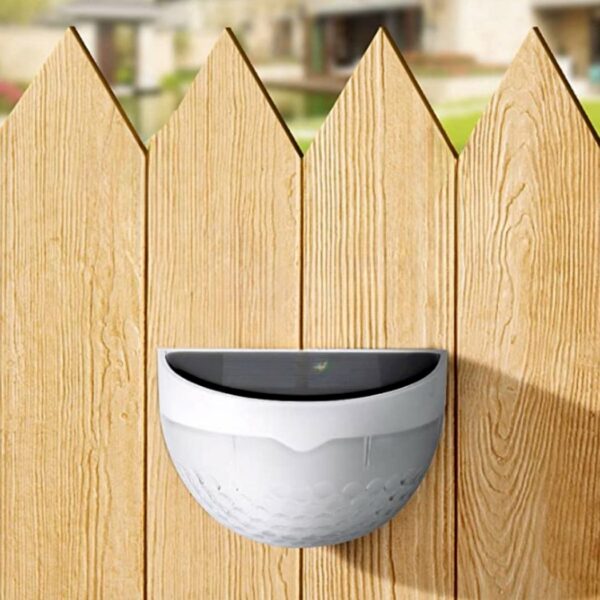 Solar-powered LED round outdoor wall light on a wooden fence