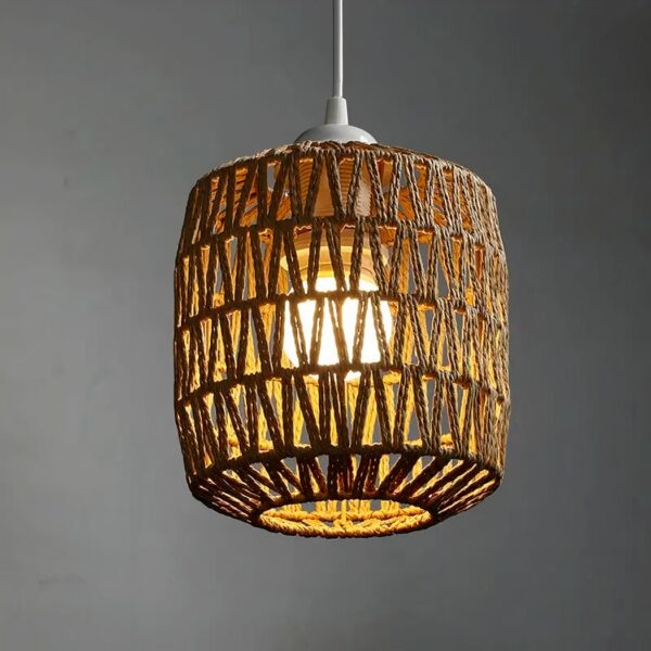 Chandelier with woven rattan shade, cylindrical shape with round opening at bottom. With lit bulb. On a gray background.