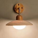 Wood wall light with a curved stone-look shade over a glass globe