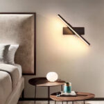 Slim bar wall light glowing diagonally above a bedside table