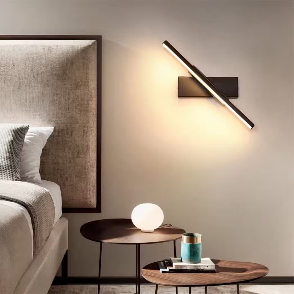 Slim bar wall light glowing diagonally above a bedside table