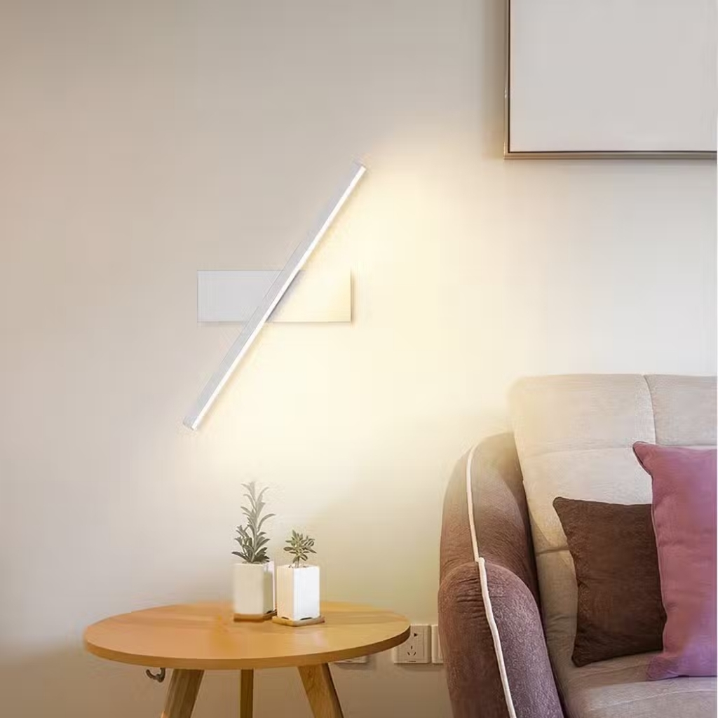 White adjustable wall lamp with a rotating light bar above a sofa