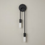 Black double-drop wall light with two staggered white cylindrical bulbs