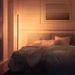 Warm white corner floor lamp glowing beside the bed in a cosy bedroom