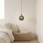 Smoked glass globe pendant light hanging above a wooden bedside table in a bedroom