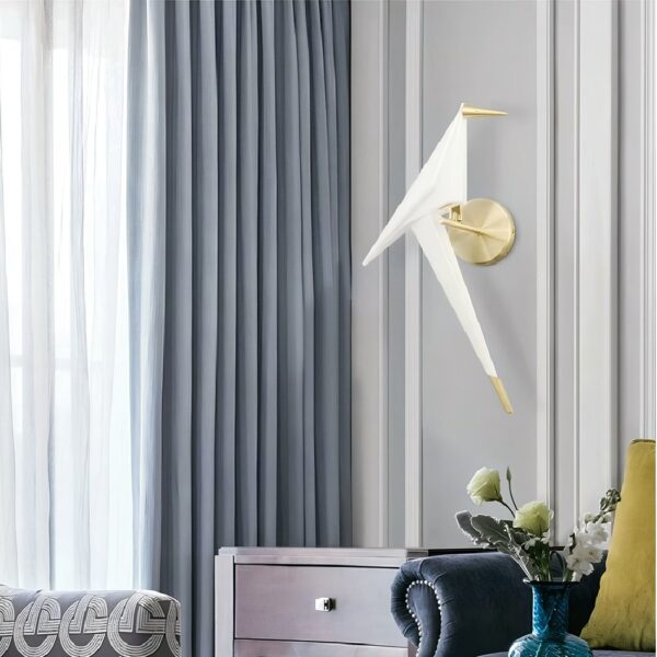 White origami bird-shaped wall light on a round brass backplate