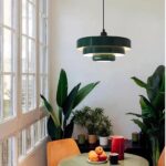 Green tiered metal pendant light hanging above a table with fruit and plants