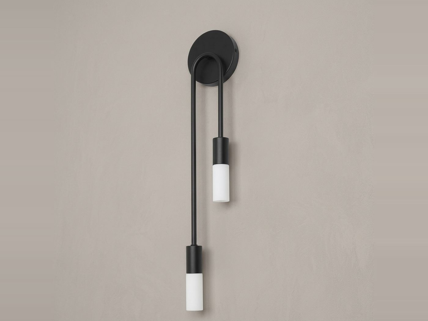Two-arm brass wall light with vertical tubes and glass diffusers beside an orange sofa
