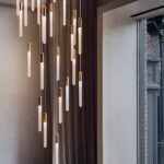 Cluster of gold-plated tube pendant lights hanging at staggered heights