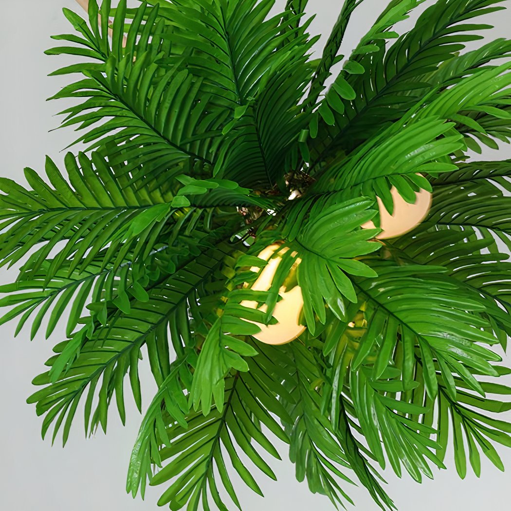 Overhead close-up of a palm leaf pendant light showing warm bulbs among green fronds