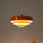 Brown and yellow tiered metal pendant light glowing warmly near dried flowers