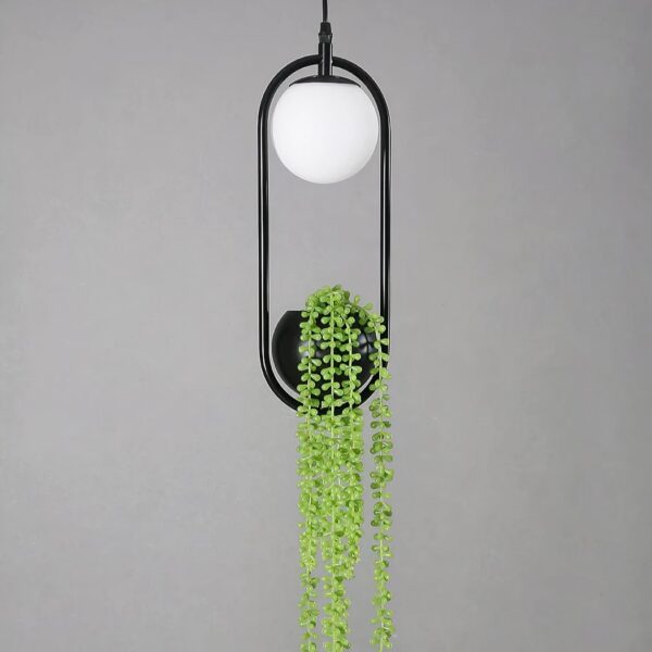 Black oval pendant light with a glass globe and trailing artificial plant