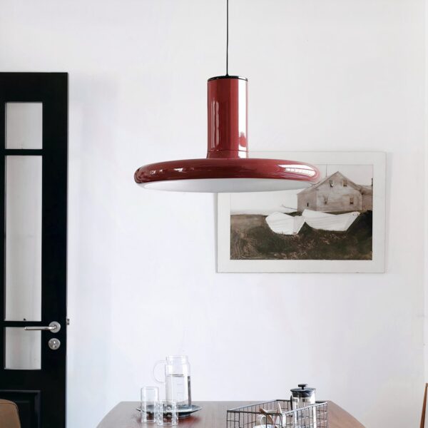 Glossy burgundy disc shaped pendant light hanging above a dining table