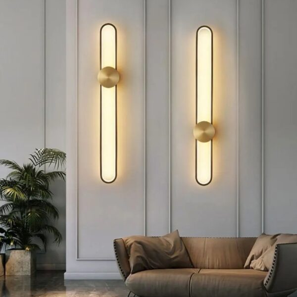 Two slim rounded LED wall lights glowing warm above a sofa