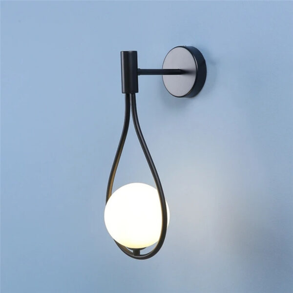 Black wall light with a teardrop shaped loop holding an opal glass ball