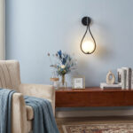 Teardrop shaped wall lamp above a wooden console table against a blue wall